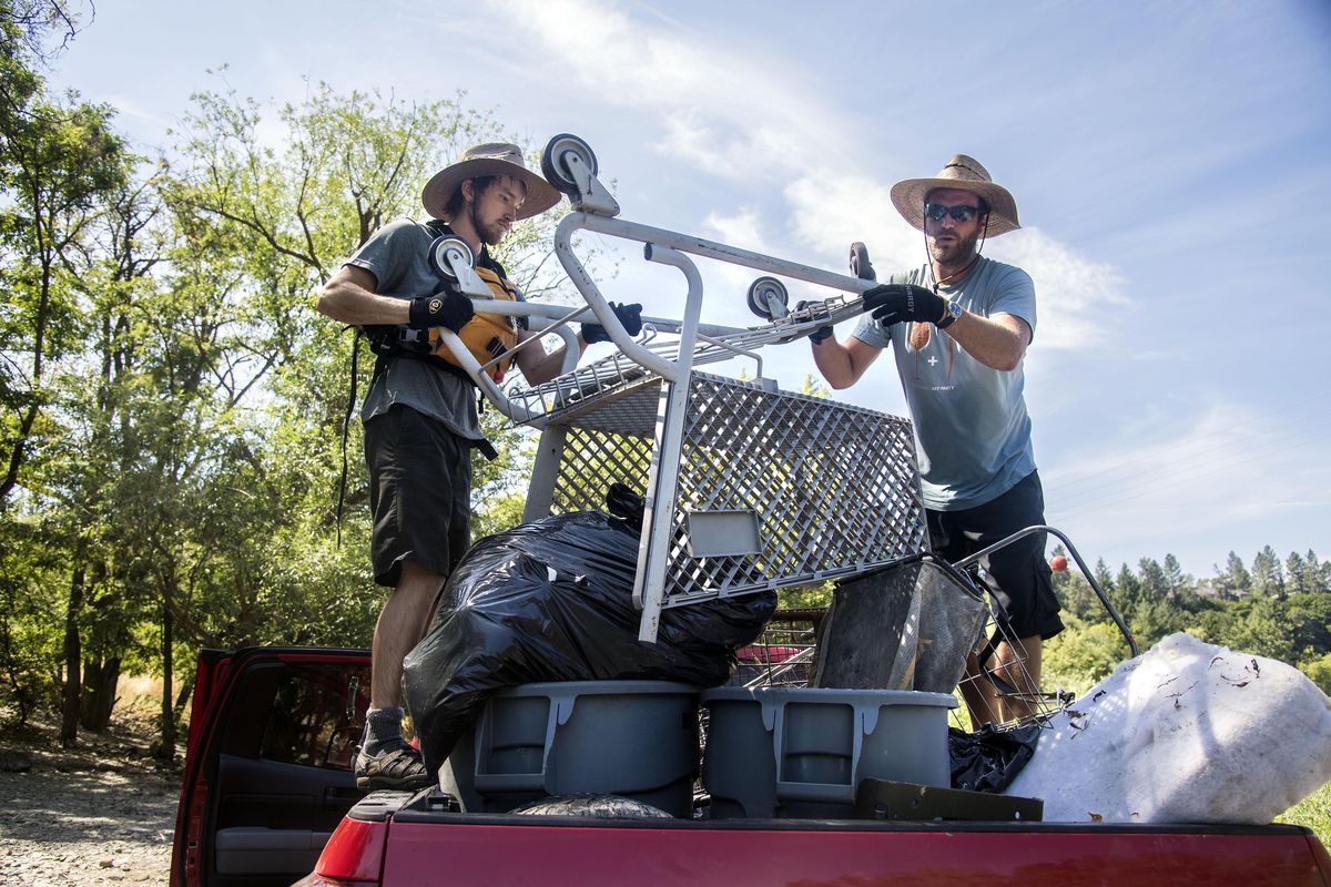 Bernt Goodson, left, and Jule Schultz, of the Spokane Riverkeeper, secure a load of trash, including a shopping cart, lawn mower bag and foam bedding, taken from a homeless camp, July 26 2017, on the Spokane River below Kendall Yards. The City of Spokane Parks and Recreation Department hauled up most of the garbage totaling an estimated 2000 pounds, while the Riverkeeper crew floated on a raft about 500 pounds to a takeout spot on the rivers south bank. (Dan Pelle / The Spokesman-Review)