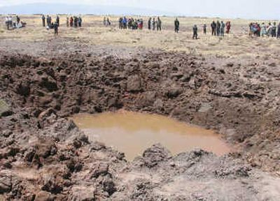 
People  stand around a meteor crater in Puno, southern Peru, on Saturday. Hundreds of people are blaming headaches, nausea and respiratory problems on the meteor. Associated Press
 (Associated Press / The Spokesman-Review)