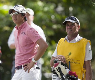 Australian Simon Clark, right, caddies for Japanese golfer Ryo Ishikawa. (Associated Press)
