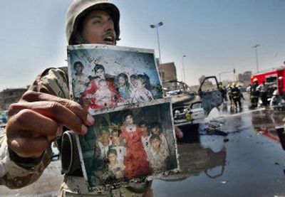 
An Iraqi soldier shouts while showing family pictures retrieved from a minibus that was blown up by a suicide bomber in a bustling open-air bus terminal in Baghdad on Friday. 
 (Associated Press / The Spokesman-Review)