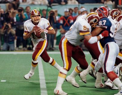 Mark Rypien, pictured at left during Super Bowl XXVI in 1992, has been sued by his longtime domestic partner alleging physical and emotional abuse over a period of 12 years. Rypien has admitted to violence in the past, and says he believes he suffers from chronic traumatic encephalopathy caused by repeated head trauma while playing football.  (Associated Press)