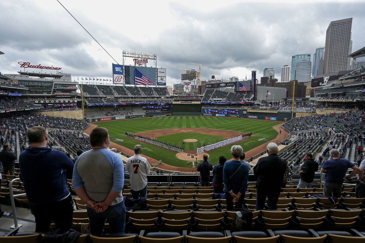 The Seattle Mariners and Minnesota Twins stand along the baselines and fans stand for the national anthem for the home opener baseball game at Target Field on April 8 in Minneapolis. Due to COVID-19 restrictions, only 10,000 fans are allowed in the ballpark.  (Bruce Kluckhohn/Associated PRess)