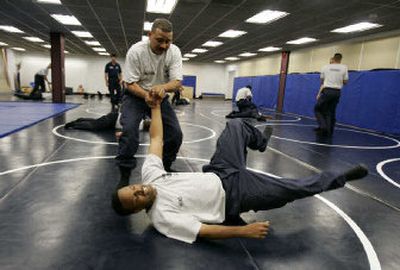 
Baltimore police officer recently recruited from Puerto Rico Angel Santana, top, takes down fellow officer Dane Hicks during a training session at the Baltimore Police Academy. Puerto Rican police and other professionals are flocking to the U.S. 
 (Associated Press / The Spokesman-Review)