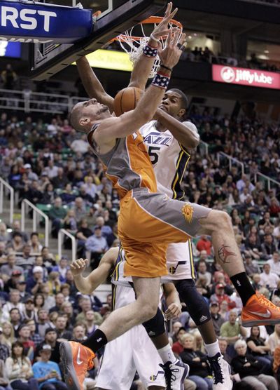Phoenix’s Marcin Gortat, left , has his shot blocked by Utah’s Derrick Favors. The Jazz, 3-0 at home, defeated the Suns 94-81. (Associated Press)