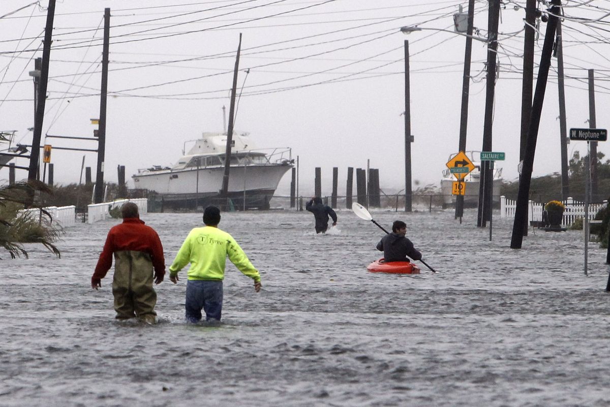 People wade and paddle down a flooded street as Hurricane Sandy approaches on Monday in Lindenhurst, N.Y. Gaining speed and power through the day, the storm knocked out electricity to millions of people. (Associated Press)