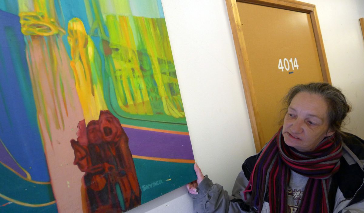 Jeannie Lawer, co-manager of the Sisters of the Road Cafe, examines a piece painted in the 1990s and now stored with scores of other pieces painted by homeless people using the organization