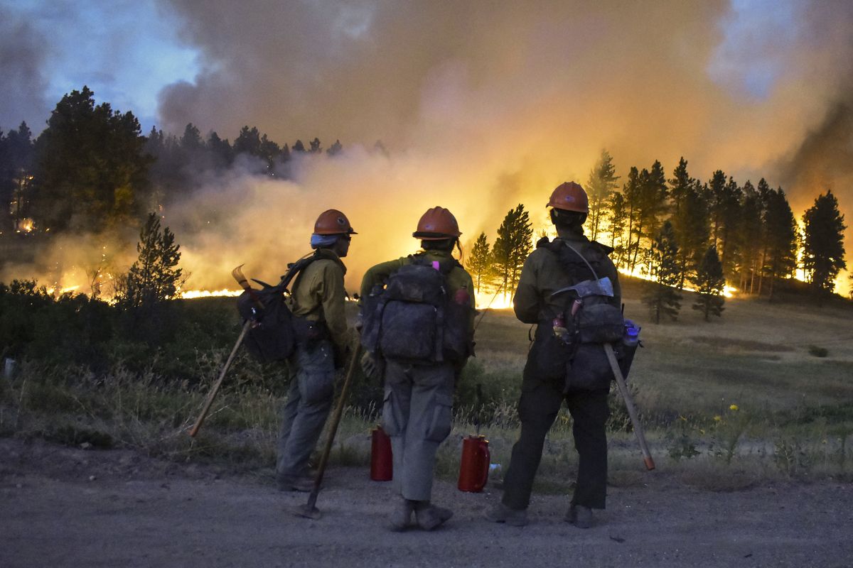 Firefighters watch a hillside burn on the Northern Cheyenne Indian Reservation, Wednesday, Aug 11, 2021, near Lame Deer, Mont. The Richard Spring fire was threatening hundreds of homes as it burned across the reservation. (Matthew Brown)