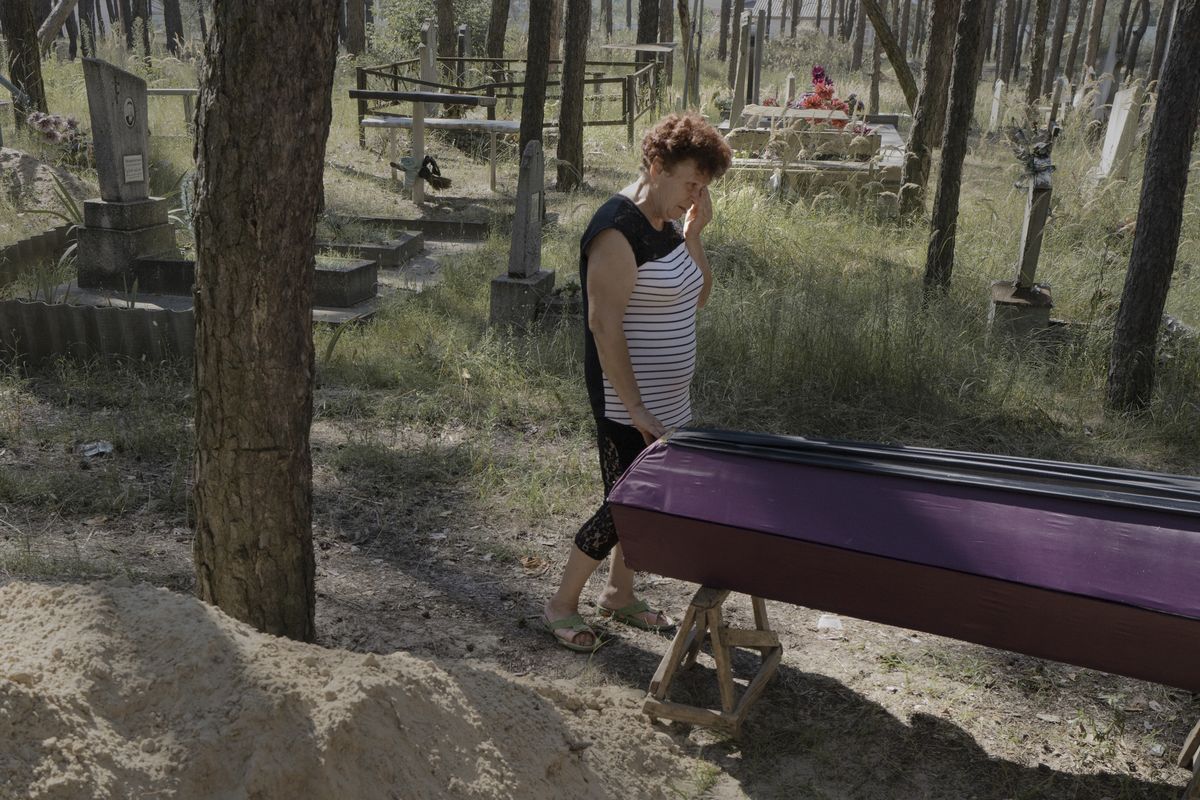 Alla Kotliarova mourns at the coffin for her mother, whose body is about to be buried for the third time, in Izium, Ukraine, Aug. 4, 2023. In this city, which was devastated during a brutal Russian occupation for six months in 2022, the trauma and fear still feel fresh for many, even though it ended almost one year ago. (Emile Ducke/The New York Times)  (EMILE DUCKE)