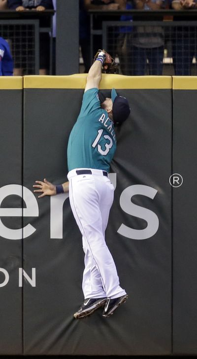 Seattle Mariners left fielder Dustin Ackley leaps at the wall and reaches over to steal a home run from New York Mets' Travis d'Arnaud in the sixth inning of a baseball game Monday in Seattle. (Associated Press)