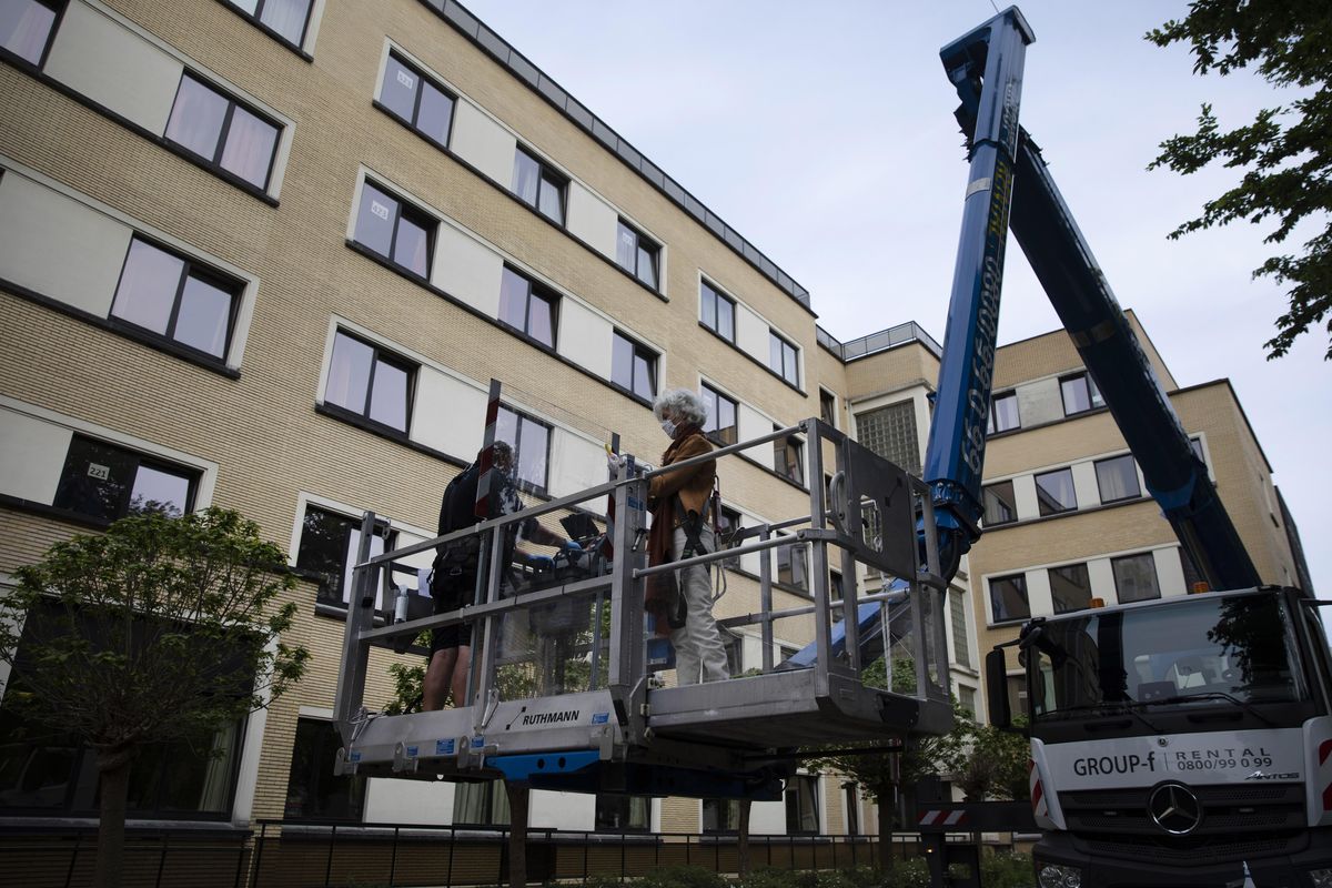 Terry Focant, right, rides on a crane platform as she prepares to visit her sister Bernadette Focant on the third floor of the La Cambre senior living home in Watermael-Boitsfort, Belgium, Saturday, May 9, 2020. Tristan Van den Bosch, an operator of mobile platforms, saw his equipment stand idle because of the coronavirus pandemic and realized too many families could not see their locked-up elderly in care homes. Two problems created one solution and Van den Bosch has been driving his cranes to care homes in several towns across Belgium to lift the spirits of all involved. (Virginia Mayo / Associated Press)