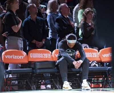 Brittany Boyd of the Liberty sits on the bench with her head bowed during the national anthem before New York’s game  against the Phoenix Mercury on Saturday. (Cooper Neill / Associated Press)