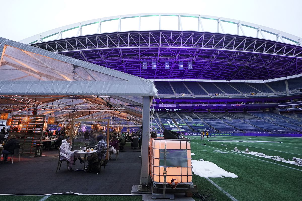 People eat dinner in an outdoor dining tent set up at Lumen Field, the home of the Seattle Seahawks NFL football team, Thursday, Feb. 18, 2021, in Seattle. The "Field To Table" event was the first night of several weeks of dates that offer four-course meals cooked by local chefs and served on the field at tables socially distanced as a precaution against the COVID-19 pandemic, which has severely limited options for dining out at restaurants in the area. (Ted S. Warren)