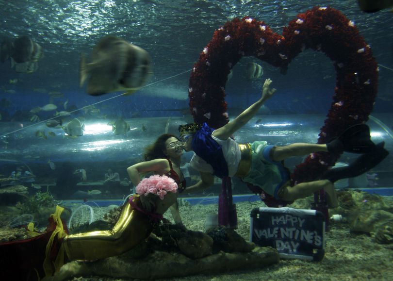 Divers portraying Poseidon and mermaid kiss each other beside a bunch of flowers in the shape of a heart during a Valentines presentation at Manila's Ocean Park Saturday, Feb. 11, 2012 in the Philippines. (Pat Roque / Associated Press)