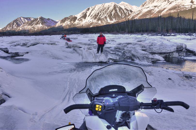 Ice bridges over open water slots at the South Fork of the Kuskokwim River near Hells Gate was one of the most treacherous sections of the Iditarod Trail negotiated in 2014 by snowmobilers Josh Rindal of Spokane, shown here waiting to help Bob Jones of Kettle Falls at dangerous spot. 