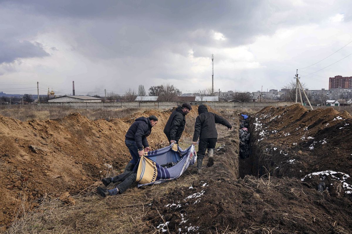 Dead bodies are put into a mass grave on the outskirts of Mariupol, Ukraine, Wednesday, March 9, 2022, as people cannot bury their loved ones because of the heavy shelling by Russian forces.  (Evgeniy Maloletka)