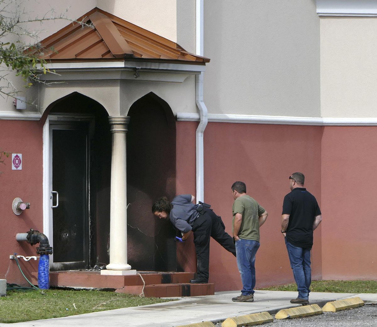 Fire officials inspect a side door where an arson took place at the Daarus Salaam Mosque in Thonotosassa, Fla., Friday, Feb. 24, 2017. (James Borchuck / AP)