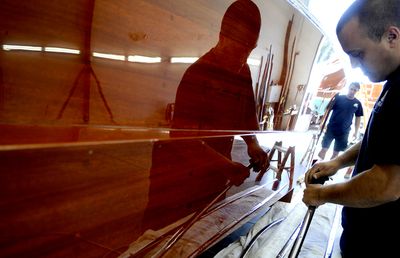 Coeur d’Alene Resort boat shop wood refinishers Mitch Devore, center, and Nick Kerfoot work to prepare a 1948 Ventnor on Tuesday for the Antique and Classic Boat Society’s International Boat Show Friday and next Saturday. (Kathy Plonka / The Spokesman-Review)