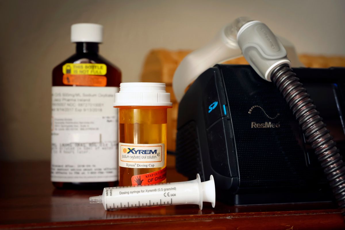 Brian Mahn's dosing cup, syringe and bottle of the drug Xyrem sit on a nightstand next to his continuous positive airway pressure, or CPAP, machine at his home in Cypress, Texas, last week.   (New York Times)
