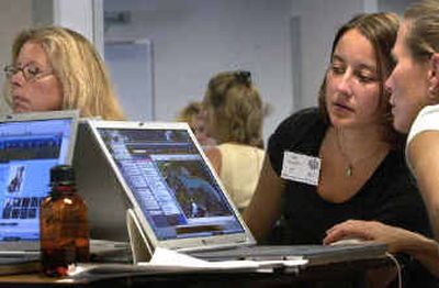 
Bemiss Elementary School teacher Kim Apaydin, center, leans over to look at colleague Barb Miller's laptop as they learn about the Encarta encyclopedia during a training session Monday afternoon. 
 (Holly Pickett / The Spokesman-Review)