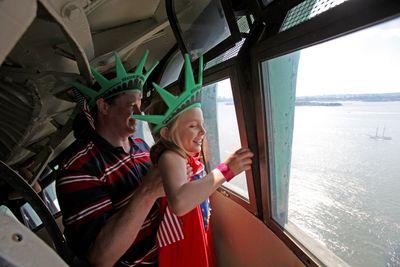 Chris Bartnick, 46, hoists his daughter Aleyna, 8, both of Merrick, N.Y., for a better view from the crown of the Statue of Liberty in New York on Saturday.  (Associated Press / The Spokesman-Review)