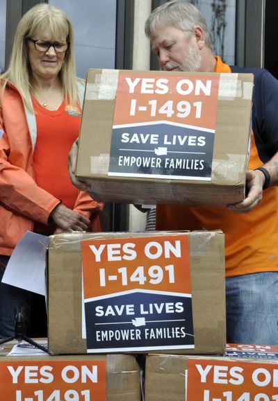 Volunteers for I-1491, a gun control initiative, stack cartons of signed petitions into a makeshift podium Thursday outside the state elections office to announce they were turning in 330,000 signatures. The measure will need slightly less than 247,000 valid signatures to make the November ballot. (Jim Camden / The Spokesman-Review)