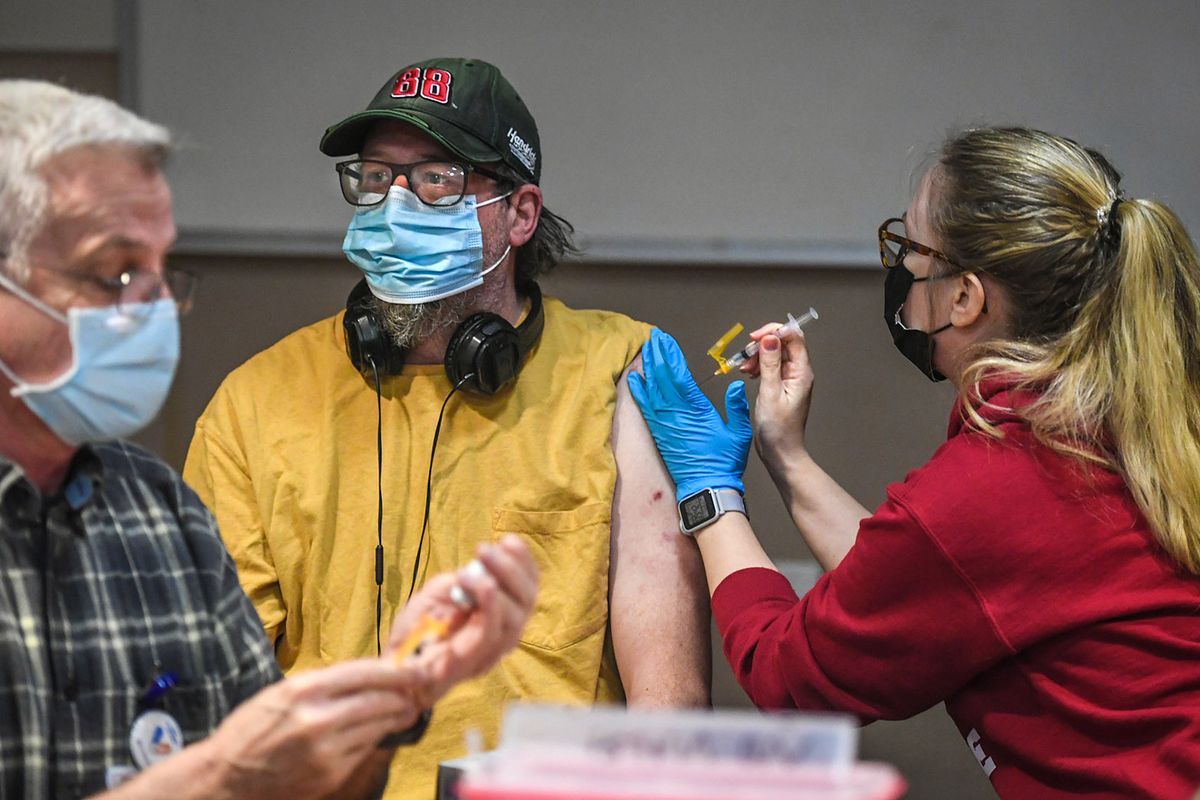 R.J Rowe, 50, center, receives his second Moderna COVID-19 vaccine from WSU nursing student Jenny Richardson, as Medical Reserve Corp volunteer Patrick McCurdy, left, loads up another dose during a Spokane Regional Health District vaccine clinic, Tuesday, March 2, 2021, at the House of Charity in downtown Spokane. (DAN PELLE/THE SPOKESMAN-REVIEW)