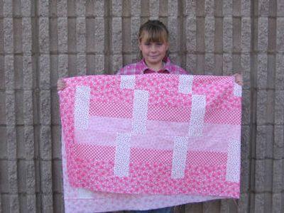 
Ashley Hanson displays a lap quilt designed for area cancer patients. With money she raised, the Riverside fourth-grader created quilt-making kits for anyone who would like to help.
 (SHANNON CARLSON / The Spokesman-Review)