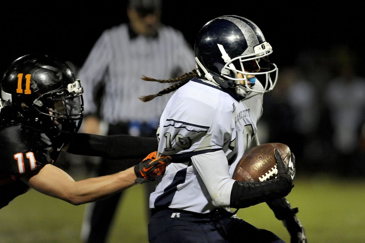 Lake City's Jerry Louie-McGee (10) tries to escape Post Falls Curtis Triplett (11) in the first half of the game at Post Falls High School on Friday, Sept. 27, 2013. (Kathy Plonka)