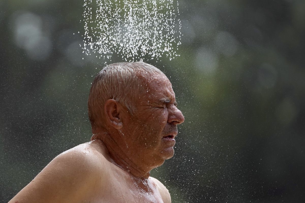 A man takes a cold shower in order to refresh himself at Ada Ciganlija Lake in Belgrade, Serbia, Wednesday, July 14, 2021. Hot weather has set in with temperatures rising up to 38 Celsius (100.4 Fahrenheit) in Belgrade.  (Darko Vojinovic/Associated Press)