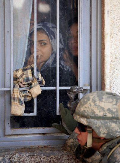 
An Iraqi woman and her sisters look on as U.S. Army Sgt. John Guerra, 21,  stands guard outside their home  during a search  in the Shaab neighborhood in Baghdad, Iraq, on Thursday. 
 (Associated Press / The Spokesman-Review)
