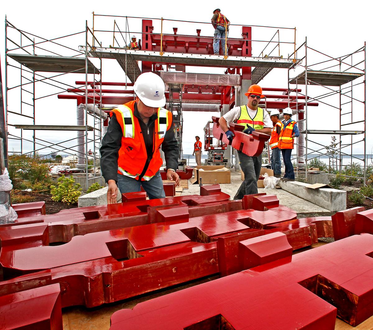 Weng Qi Hua, left, from Tacoma’s sister city Fuzhou, China, helps Heath Carlson of Clements Brothers Construction gather pieces of a traditional pagoda during the first full week of construction on Sept. 21. (Associated Press)