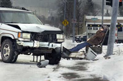 
Andrew Weeks uses his cell phone to call for help after crashing his Jeep into the light pole at Euclid and Crestline on Tuesday. A snow storm left Spokane streets icy, and the resulting wrecks kept police and towing companies busy. 
 (CHRISTOPHER ANDERSON / The Spokesman-Review)