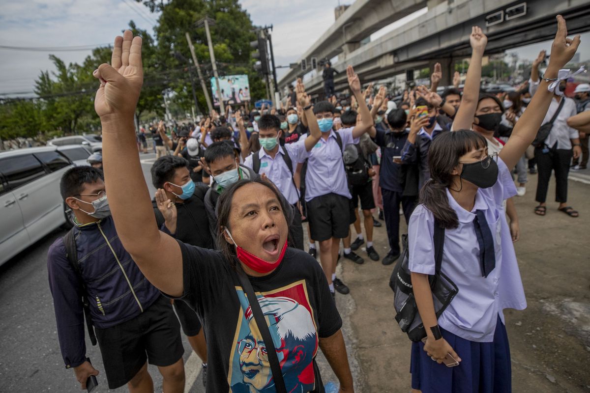 Pro-democracy protesters flash three-fingered salute during a demonstration at Kaset intersection, suburbs of Bangkok, Thailand, Monday, Oct. 19, 2020. Thailand's embattled Prime Minister Prayuth Chan-ocha said Monday that there were no plans to extend a state of emergency outside the capital, even as student-led protests calling for him to leave office spread around the country.  (Sakchai Lalit)
