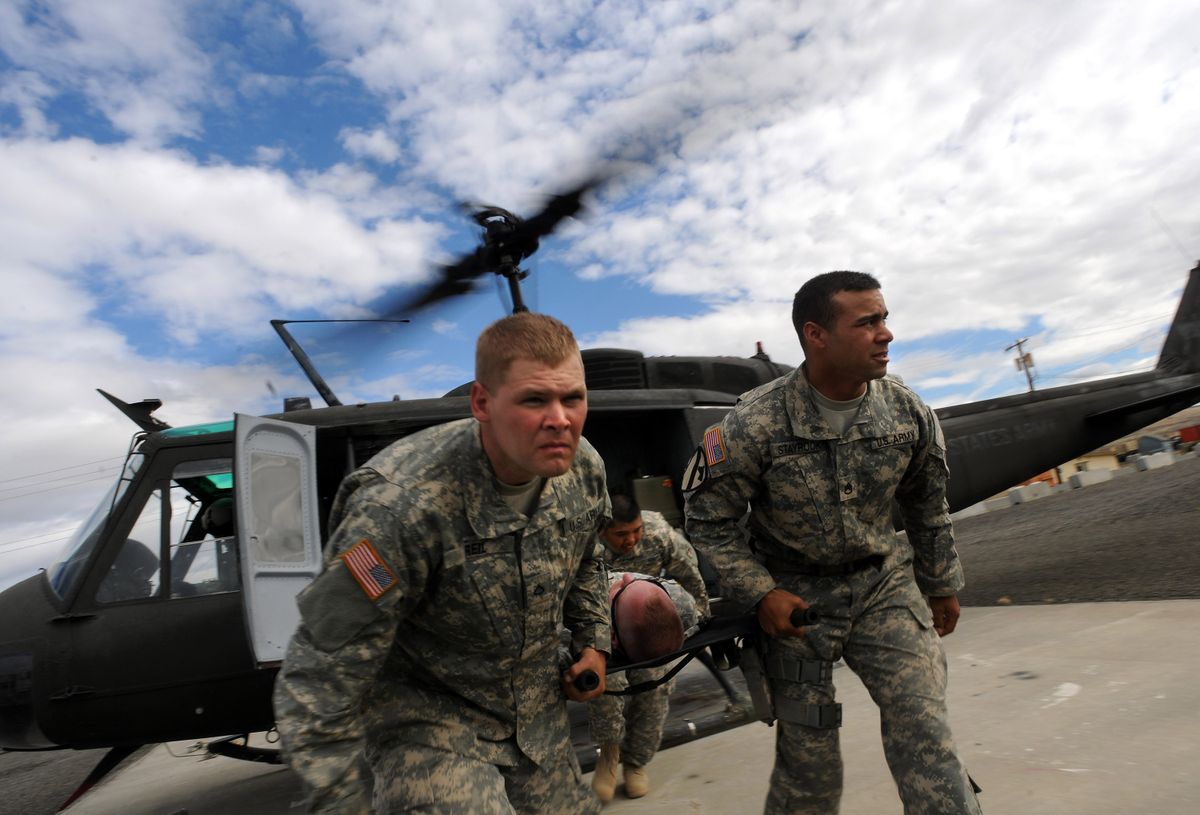 Pvt. First Class Vincent Reil, left, and Staff Sgt. Matthew Staybrook duck under the blades of Huey Medivac helicopter at the Yakima Firing Range   on Friday. (Rajah Bose / The Spokesman-Review)