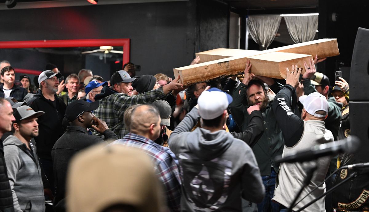 The crowd of mostly men gathered inside the former Deja Vu Showgirls building passes around a simple wooden cross before positioning it on the former stage inside the club Saturday in Spokane Valley.  (Jesse Tinsley/THE SPOKESMAN-REVIEW)