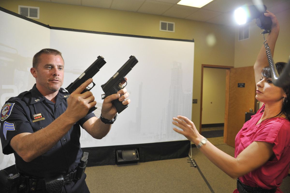 Monique Cotton, right, assists with photographing Spokane Police Department Range Master Sgt. Chris Crane in July  2014. Cotton was the police spokeswoman at the time. (Dan Pelle)