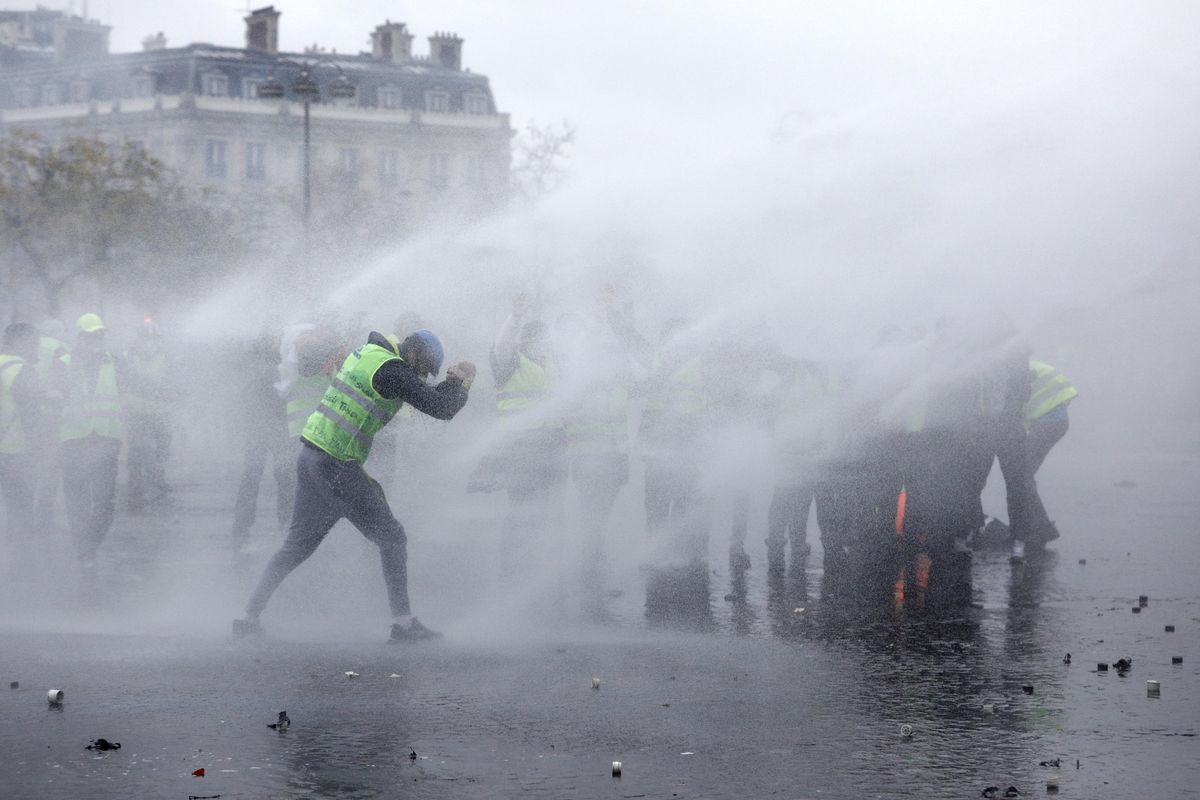 Demonstrators wearing yellow jackets face water cannons near the Champs-Elysees avenue during a demonstration Saturday, Dec.1, 2018 in Paris. French authorities have deployed thousands of police on Paris’ Champs-Elysees avenue to try to contain protests by people angry over rising taxes and Emmanuel Macron’s presidency. (Kamil Zihnioglu / AP)