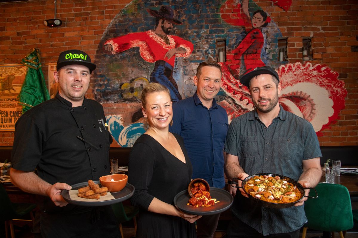 De España chef Erik Strandberg, wine manager Nicole Seaman, owner Adam Hegsted and Aaron Fish, chef for Eat Good Group, hold the restaurant’s popular items, including a churro, patatas bravas and a classic paella.  (Jesse Tinsley/THE SPOKESMAN-REVI)