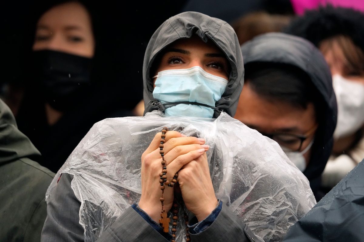 A woman holding a rosary waits for Pope Francis to deliver the Urbi et Orbi (Latin for 