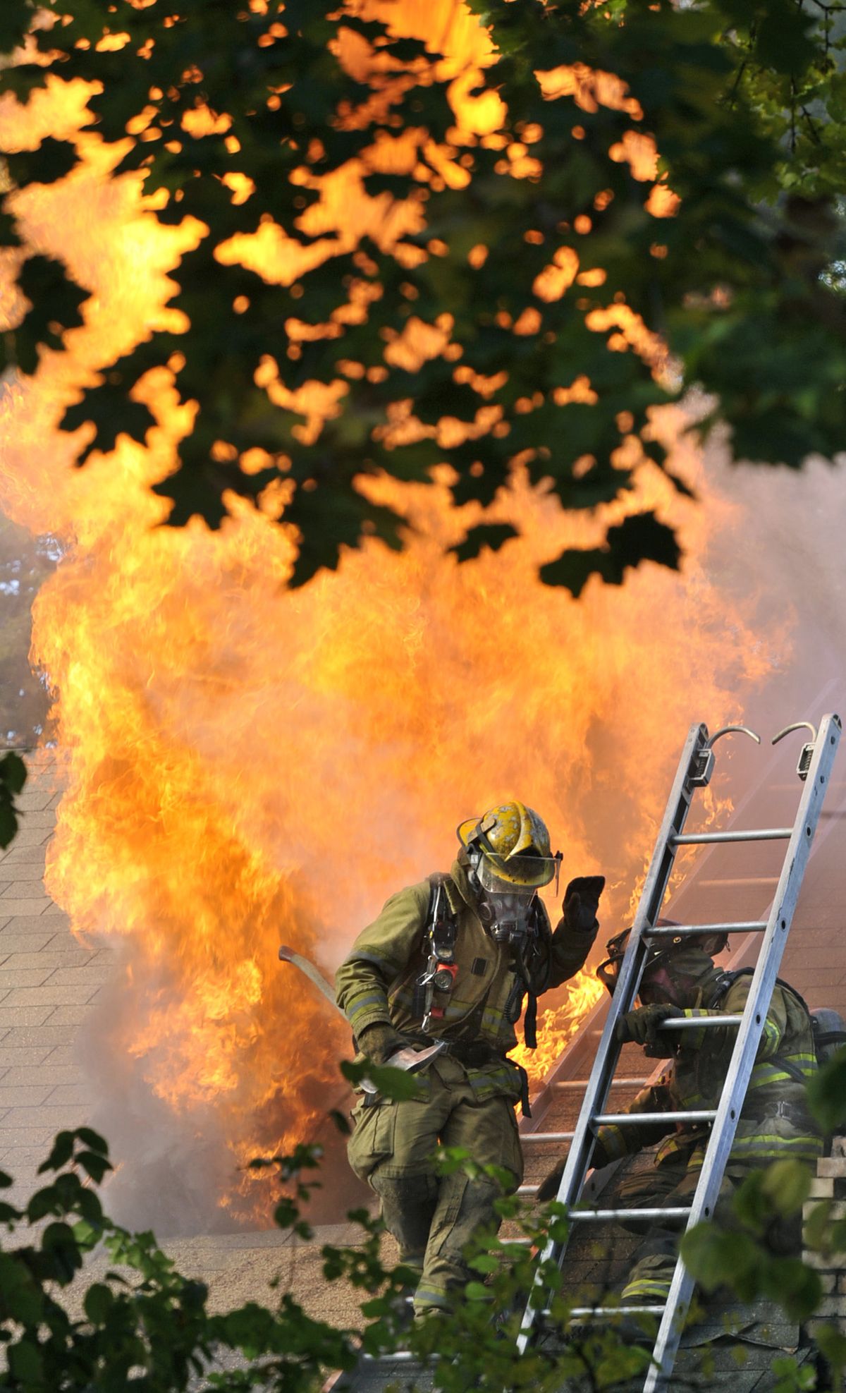 After venting a garage roof, Spokane Fire Department firefighters scramble for safety as flames explode near Pacific Avenue and Hemlock Street Tuesday.  (Dan Pelle / The Spokesman-Review)