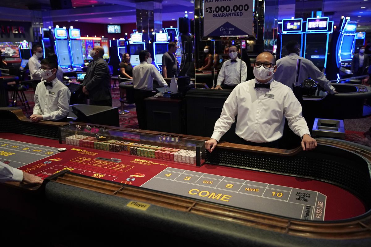 FILE - Dealers in masks wait for customers before the reopening of the D Las Vegas hotel and casino in Las Vegas, in this Wednesday, June 3, 2020, file photo. Governments and businesses are scrambling to change course following new federal guidance calling for the return of mask wearing in virus hot spots amid a dramatic spike in COVID-19 cases and hospitalizations nationwide. Nevada and Kansas City were among the locations that moved swiftly to re-impose indoor mask mandates following Tuesday’s announcement from the Centers for Disease Control and Prevention.  (John Locher)