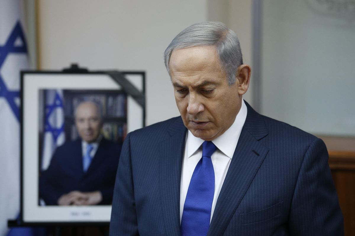 Israeli Prime Minister Benjamin Netanyahu observes a moment of silence as he stands next to a photograph of former Israeli President Shimon Peres at the start of a special cabinet meeting to mourn the death of Peres, in Jerusalem, Wednesday, Sept. 28, 2016. (RONEN ZVULUN / Associated Press)