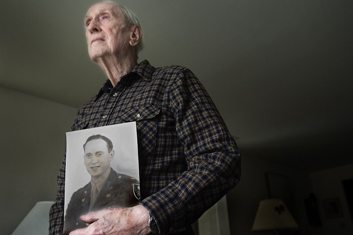 John Wills holds a photo of himself in his military uniform at his Spokane home in 2007. (File)