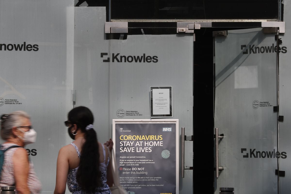 Two women stand outside a closed branch of a shoe shop in Kensington, London, Wednesday, Aug. 12, 2020. The British economy is on course to record the deepest coronavirus-related slump among the world