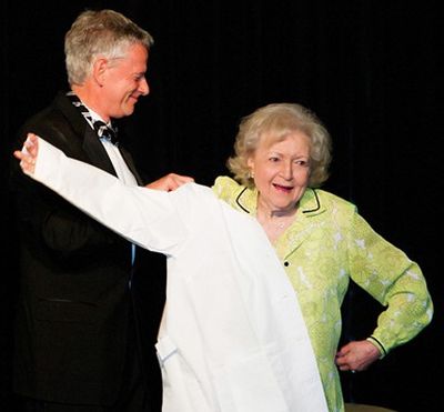 Provost Warwick Bayly presents legendary comedian and actress Betty White a ceremonial white doctor's coat Oct. 8, 2011, in Yakima, Wash., as White was made an honorary alumna of WSU's College of Veterinary Medicine. (Washington State University)