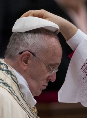 Pope Francis is helped wearing his skull cap as he arrives to celebrate the new year's eve vespers Mass in St. Peter's Basilica at the Vatican, Wednesday, Dec. 31, 2014. The traditional Mass on Dec. 31contains the thanksgiving hymn ''Te Deum' for the ending year and is the last public appearance of the pope in 2014. (Andrew Medichini / Associated Press)