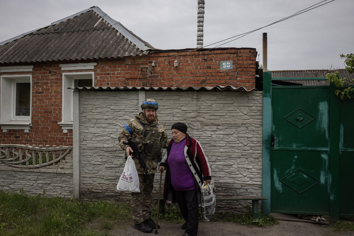 Kateryna Yefemets, 70, speaks to Oleksii Kharkivskyi 35, head of patrol police in Vovchansk, before she gets in a police car to be evacuated during a Russian advance into the Kharkiv region on Monday.  (Ed Ram/For The Washington Post)