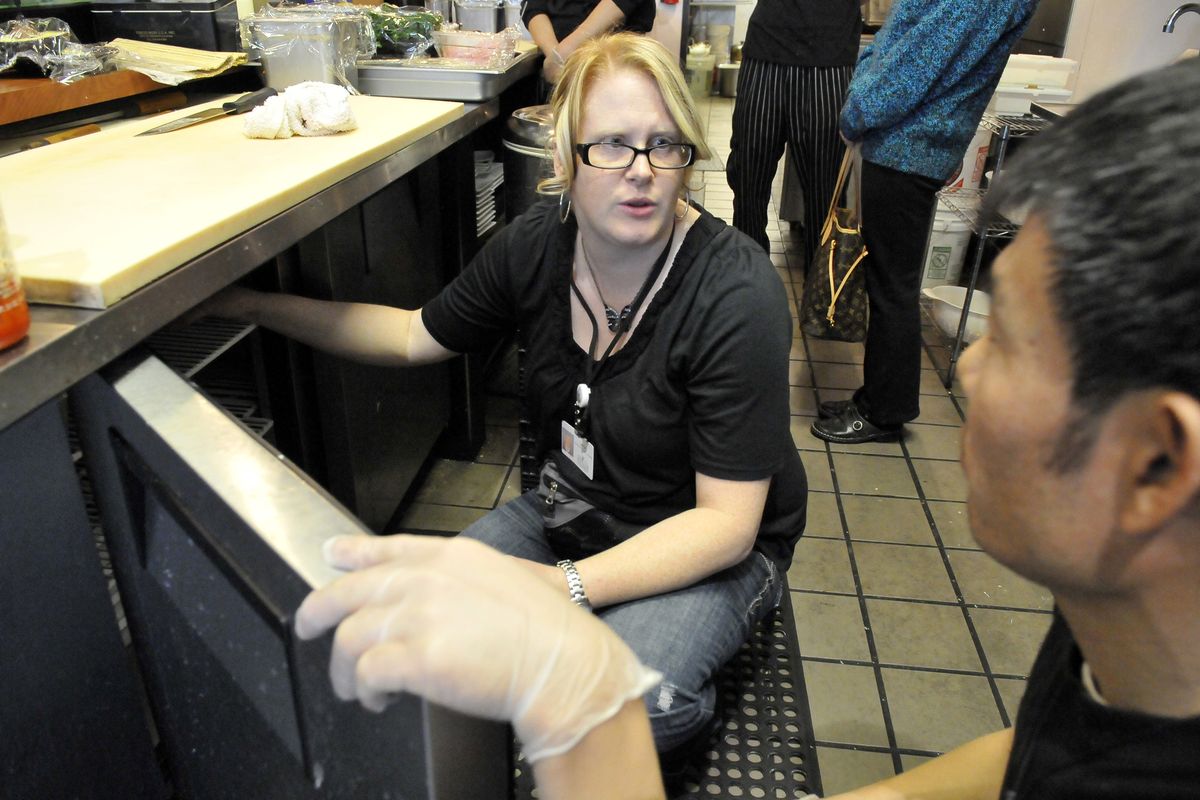 Vikki Barthels, an environmental health specialist with the Spokane Regional Health District, talks with a chef while checking the temperature in an under-counter cooler at Sushi I on the South Hill recently. Food safety programs that focus on food service businesses are part of the core mission of the regional health district at a time when many other programs are being cut back or cut altogether. (Jesse Tinsley)