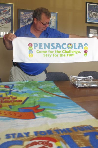 Ray Palmer, director of the Pensacola Sports Association, displays a sports towel and fleece blanket in Pensacola, Fla. (Associated Press)