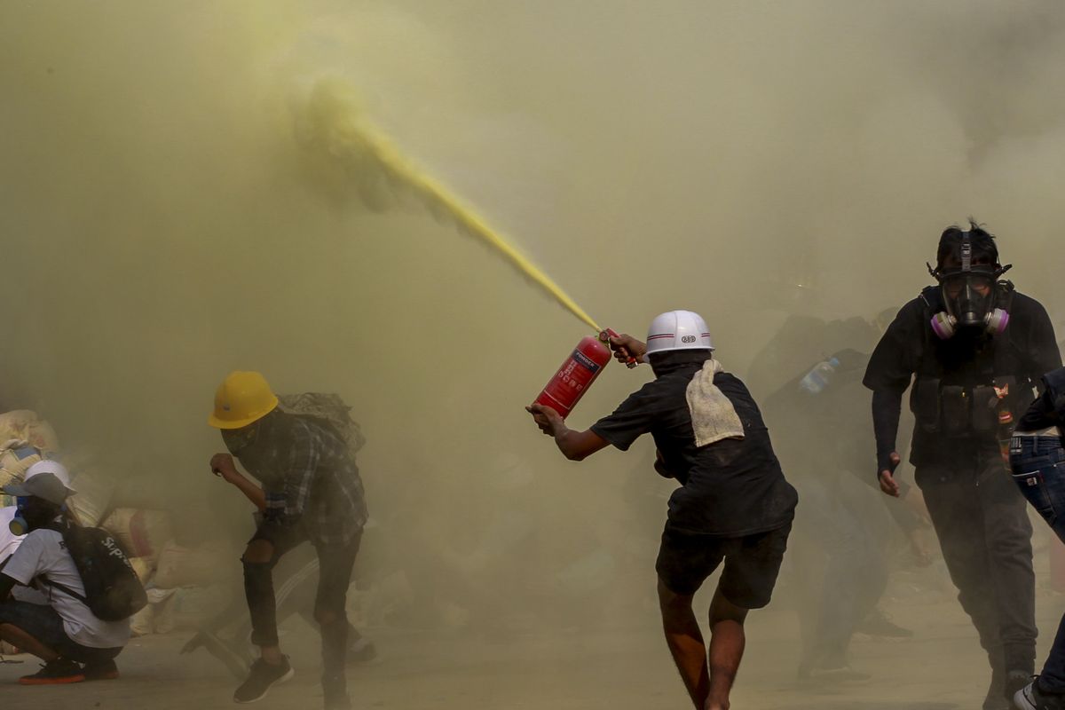 An anti-coup protester uses a fire extinguisher to provide cover for others as security forces approach their encampment in Yangon, Myanmar, Wednesday, March 17, 2021.  (STR)